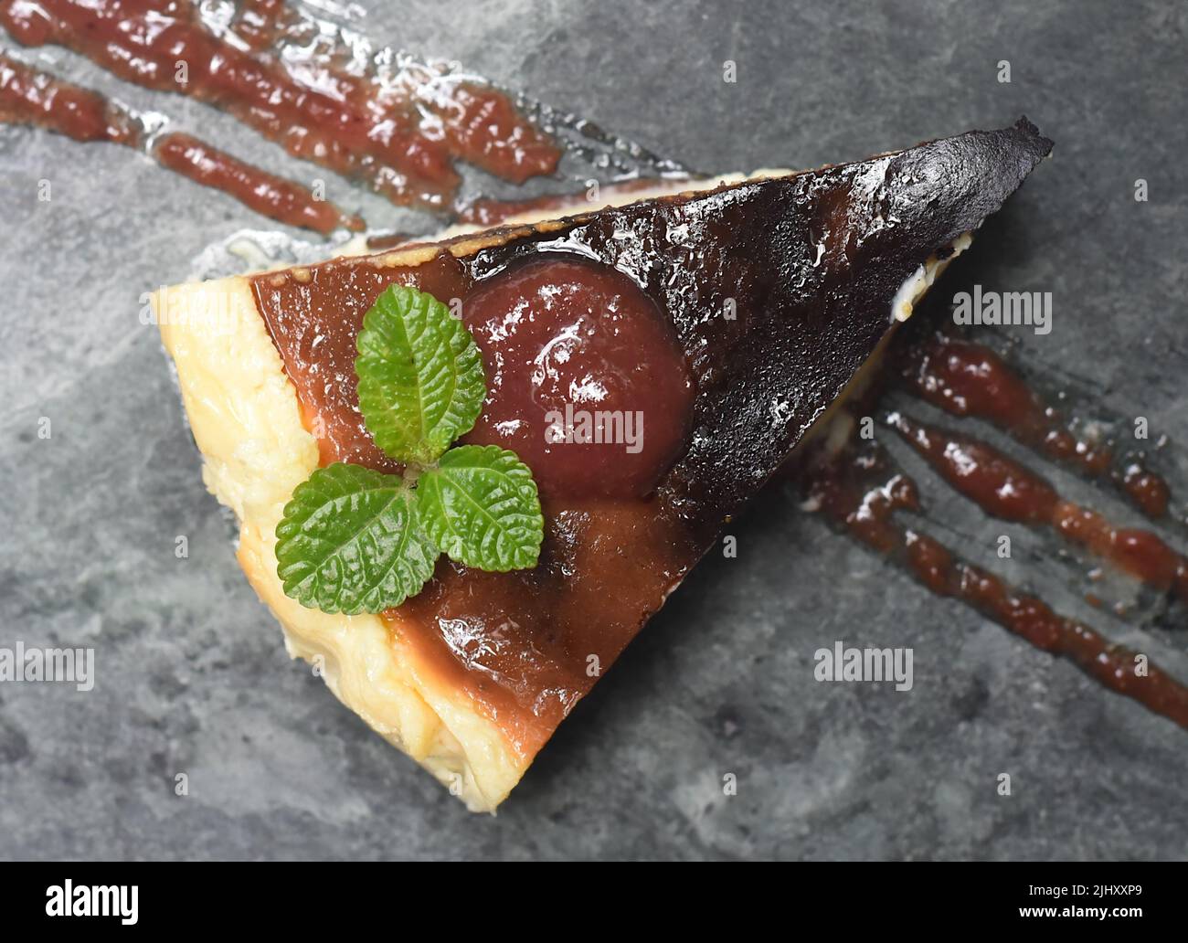 Cheesecake brûlé sur une plaque de pierre avec une feuille de menthe qui bascule sur fond gris de pierre Banque D'Images