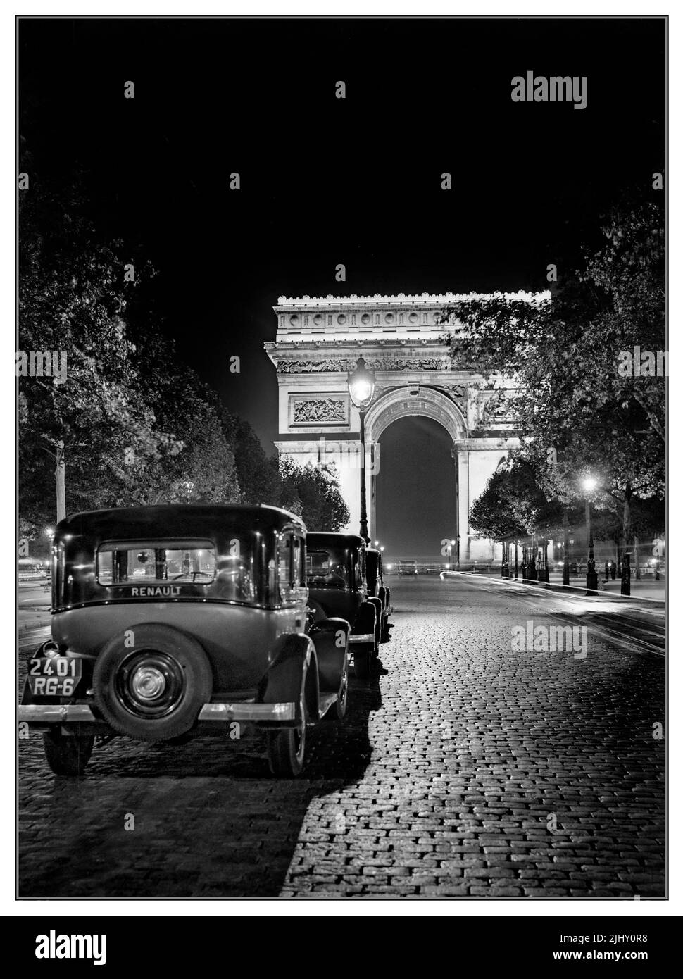 Vintage 1930s Paris et l'Arc de Triomphe la nuit avec une ligne de Renault taxis français en ligne sur les champs Elysées pavées Paris France Banque D'Images