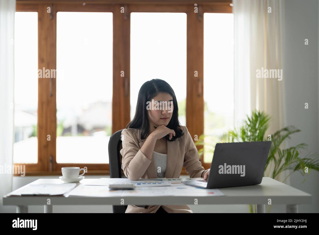 Femme d'affaires utilisant la calculatrice pour faire des finances mathématiques sur le bureau en bois dans le bureau et les affaires de travail, la fiscalité, la comptabilité, les statistiques et l'analytique Banque D'Images