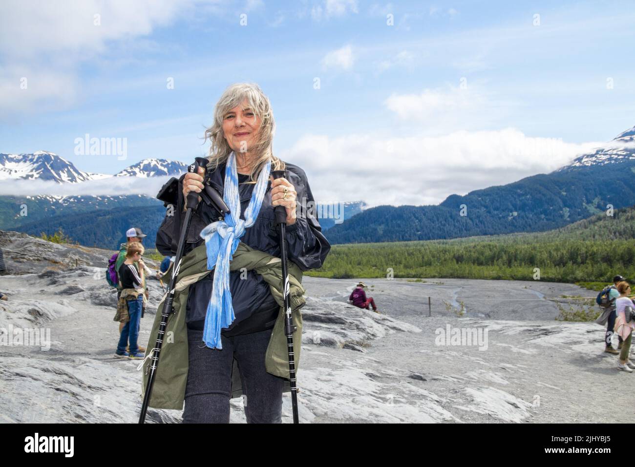 2022 06 24 sortie Glacier Alaska USA dame senior randonnée sur terrain accidenté en utilisant des bâtons de randonnée - manteau attaché autour de la taille - nos touristes et de montagnes brumeuses Banque D'Images