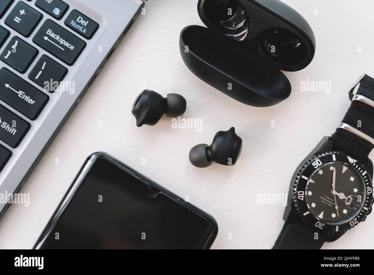 Ordinateur portable, smartphone, casque sans fil et montre sur fond blanc. Gadgets modernes. Vue de dessus Banque D'Images