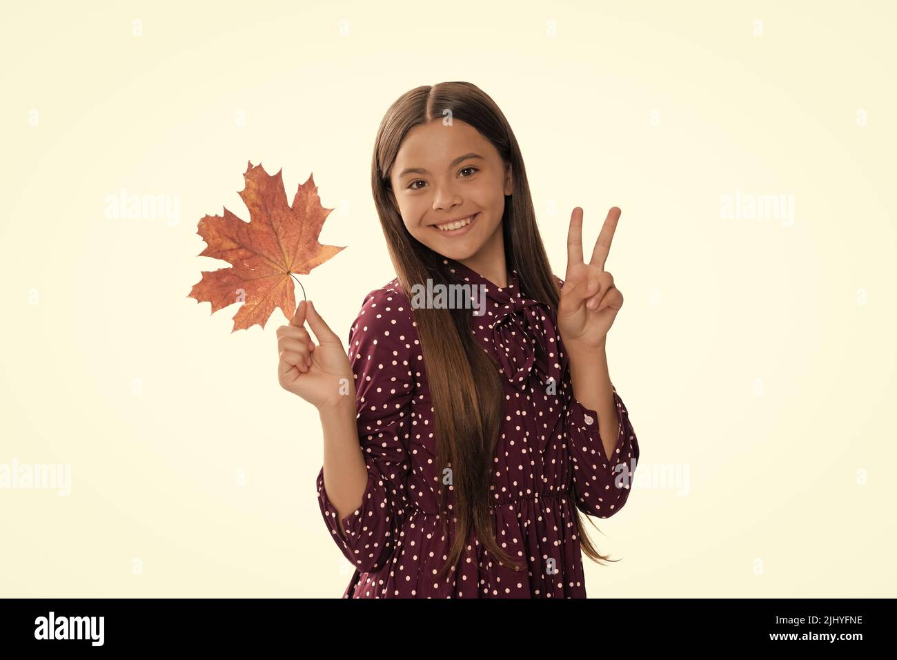 bonne jeune fille en automne avec feuille d'érable isolée sur blanc montrant le geste de paix, la nature Banque D'Images