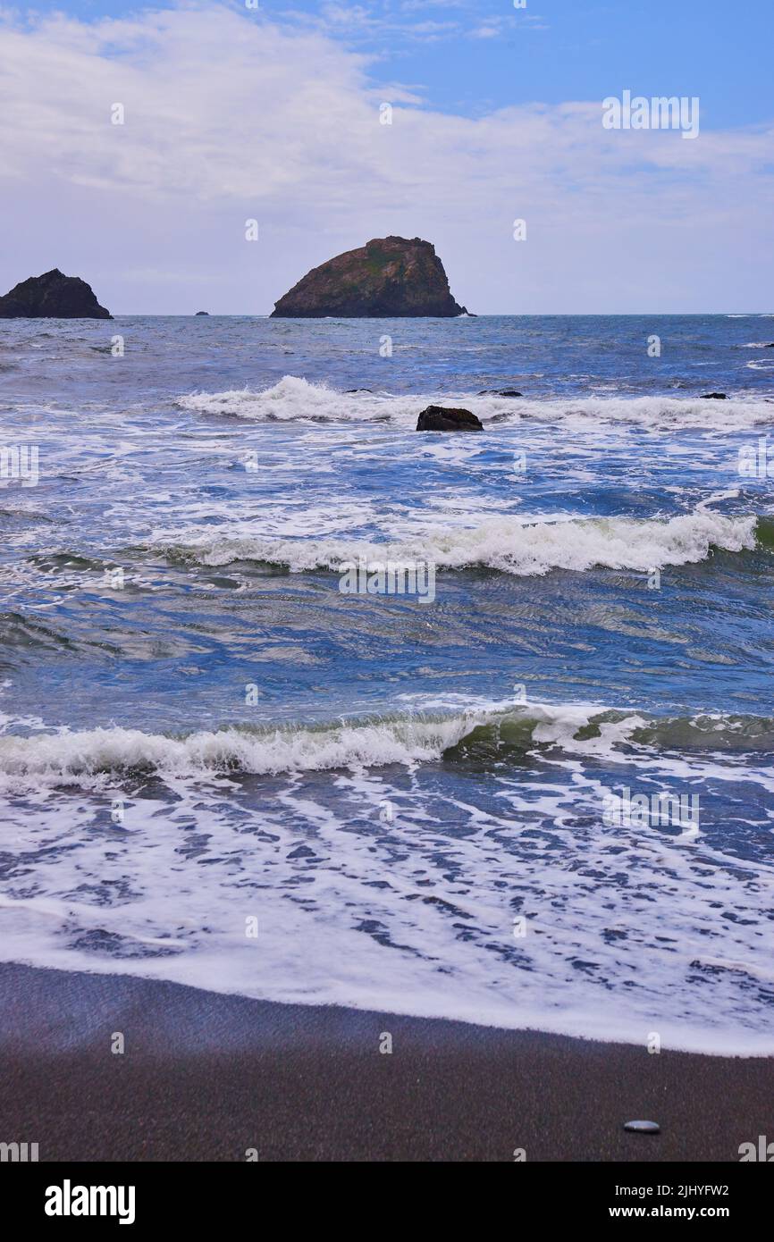 Image de la plage de sable noir de la côte ouest avec de petites vagues qui s'écrasant Banque D'Images