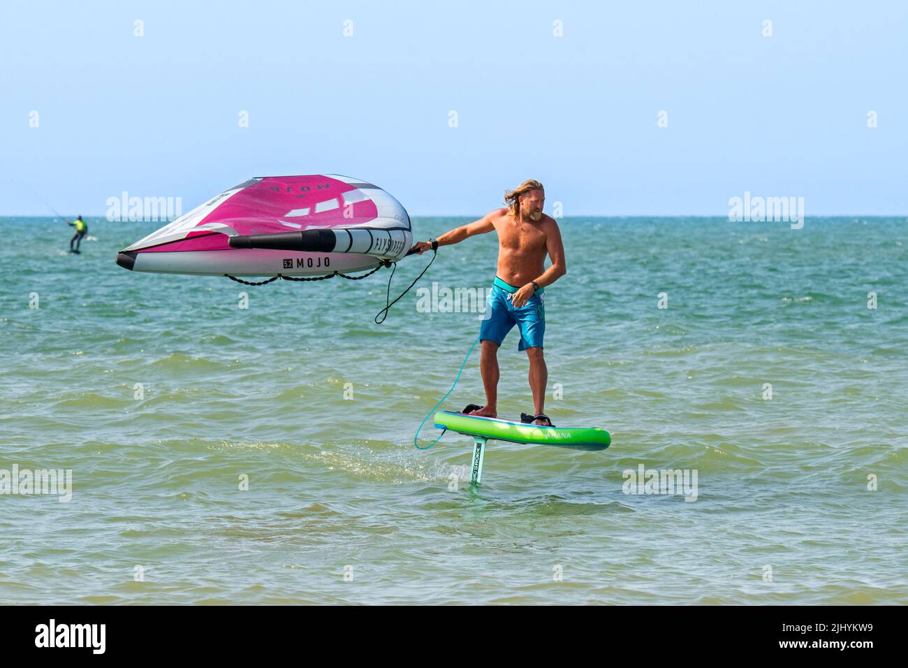 Voile d'aile / surf d'aile sur la mer du Nord montrant le wingboarder / le boarder d'aile debout sur le foilboard / hydrofoil et tenant une aile gonflable Banque D'Images