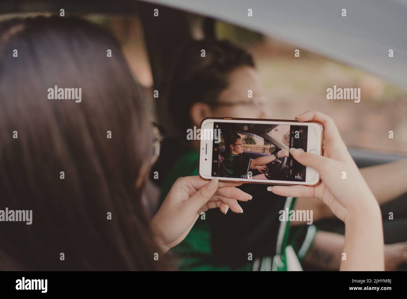 adolescent photographiant une autre personne avec un téléphone blanc Banque D'Images