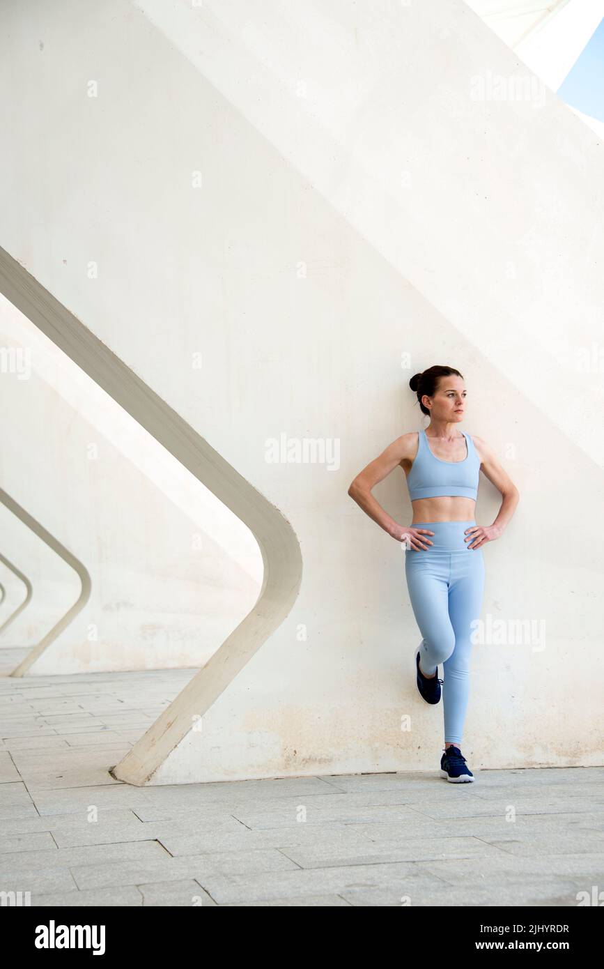 femme se penchant contre un mur de béton au repos pendant l'entraînement, Banque D'Images