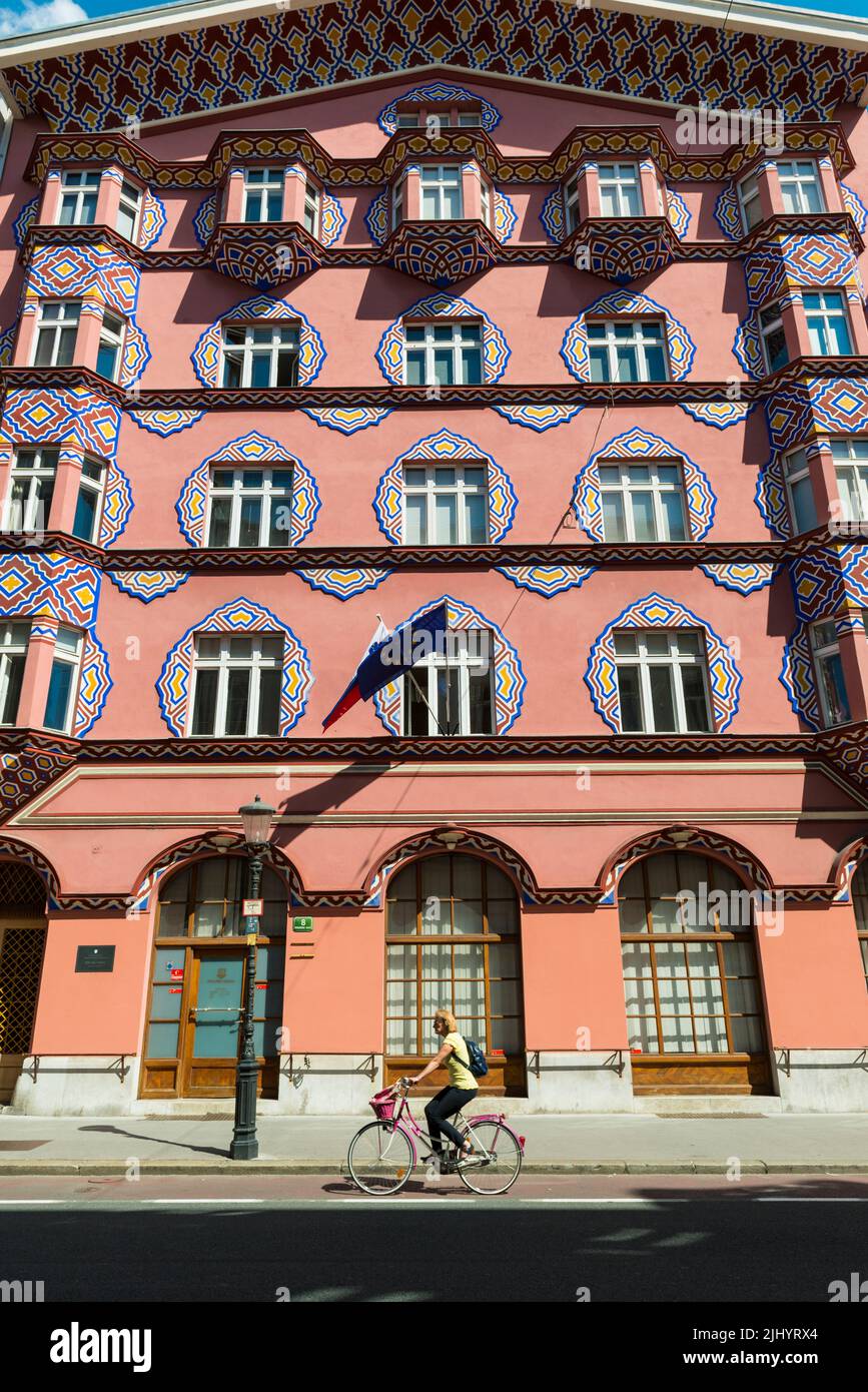 Une cycliste féminine passe devant la façade du bâtiment de la Banque coopérative conçu par l'architecte Ivan Vurnik et sa femme Helena Vurnik. Ljubljana, Slovénie. Banque D'Images