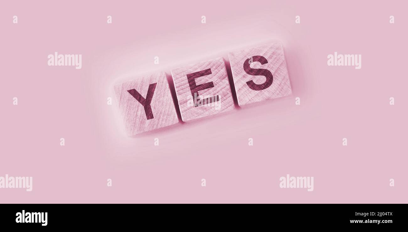 Cubes en bois avec le mot OUI sur la table rose. Réponse positive et concept de réflexion positive Banque D'Images