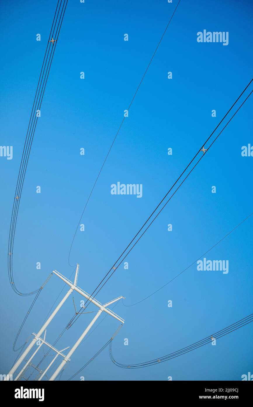 Un poteau moderne de distribution d'énergie hydro-électrique avec des câbles contre le ciel bleu un matin ensoleillé. Banque D'Images