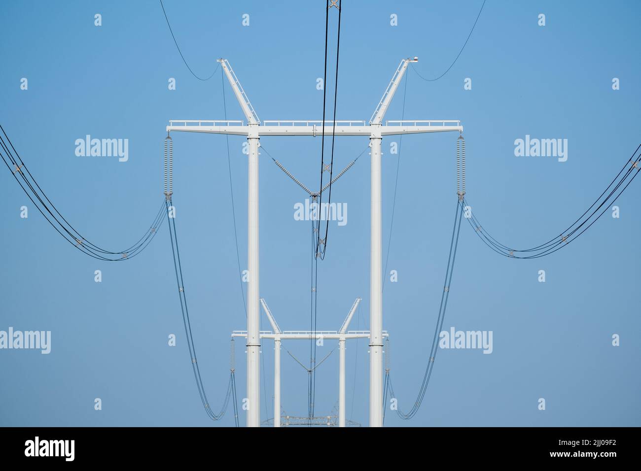 Poteaux modernes de distribution d'énergie hydro-électrique avec des câbles contre le ciel bleu un matin ensoleillé. Banque D'Images