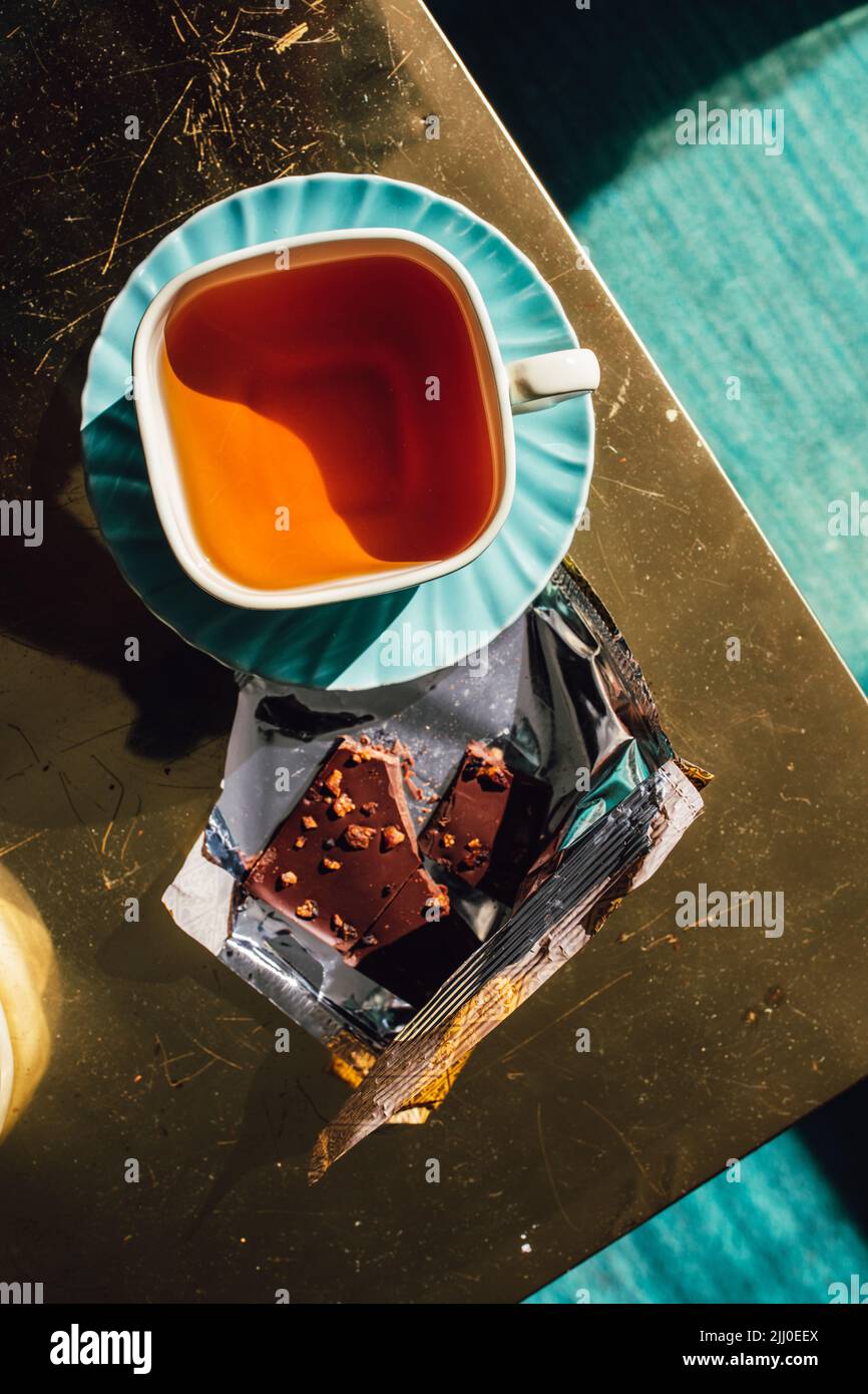 thé de l'après-midi dans la tasse carrée de thé et soucoupe avec chocolat dans l'emballage doré Banque D'Images