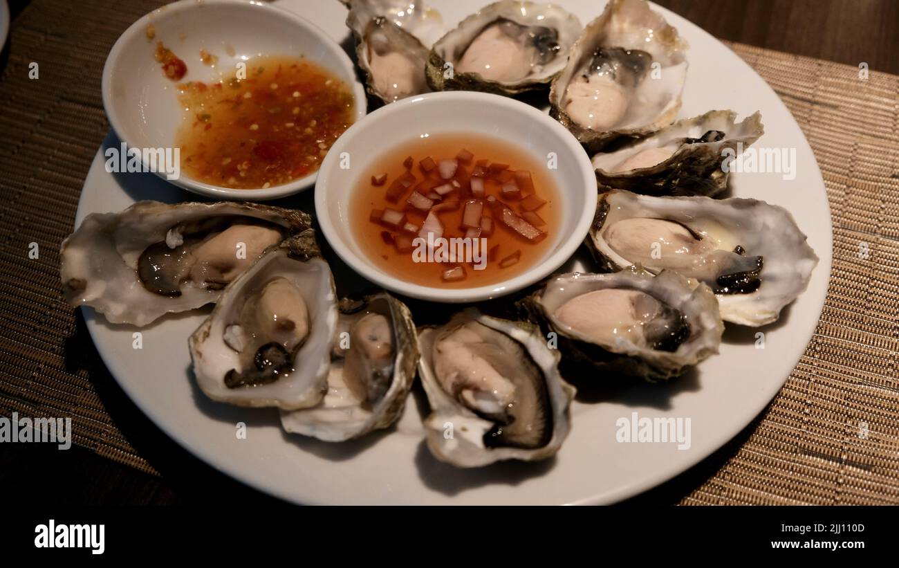 Assiette d'huîtres crues fraîches avec vinaigrette et sauce épicée Banque D'Images