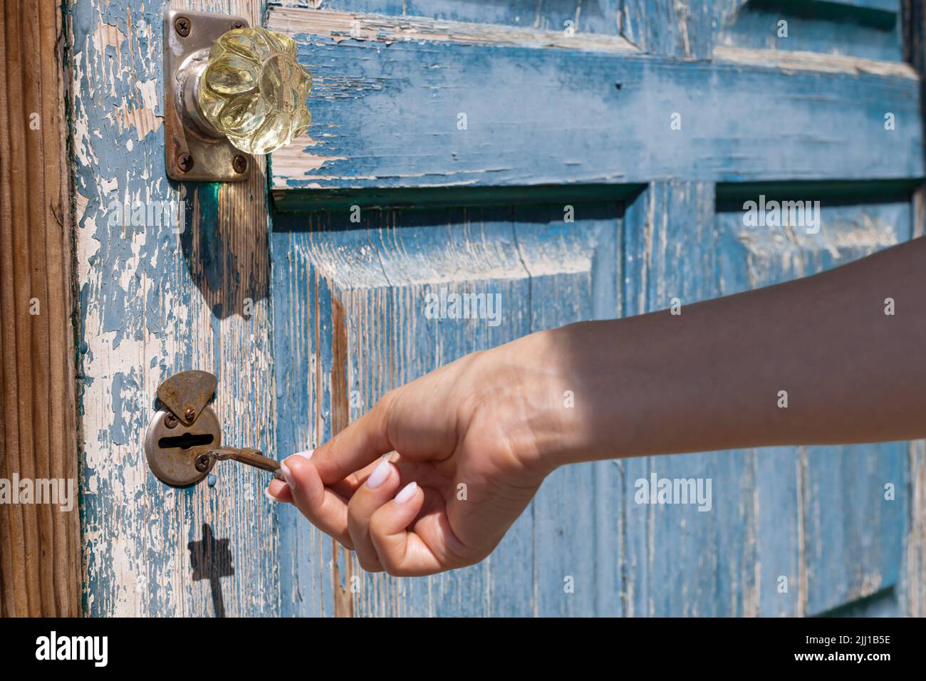 une main femelle ouvre la serrure de porte avec une clé rouillée. Photo de haute qualité Banque D'Images