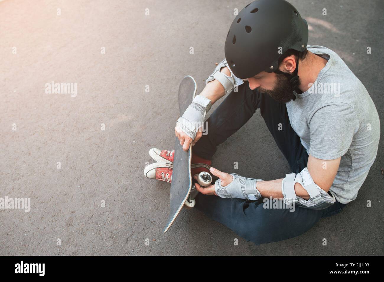 Un patineur professionnel vérifie son skateboard Banque D'Images