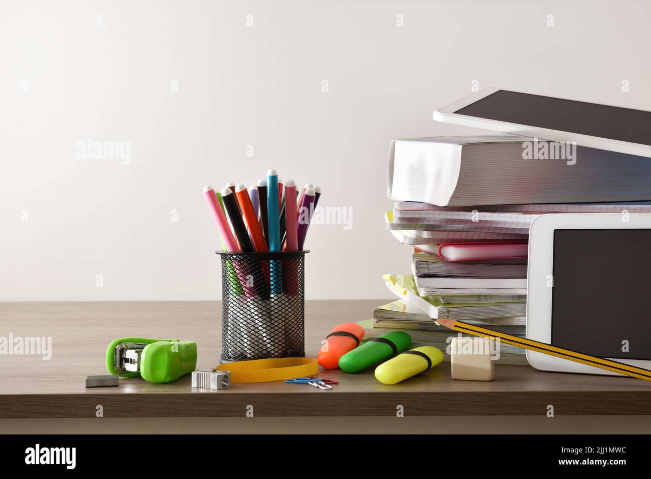 Fournitures scolaires, livres, carnets et tablettes électroniques sur table en bois et fond blanc isolé. Vue avant Banque D'Images