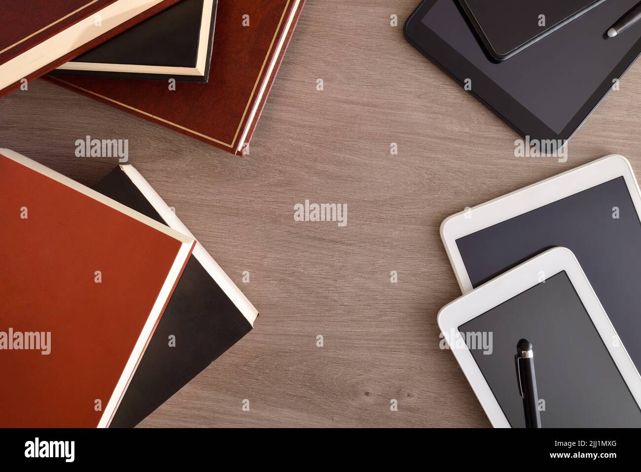 Comparaison entre les livres papier traditionnels et les lecteurs électroniques sur table en bois. Vue de dessus. Banque D'Images