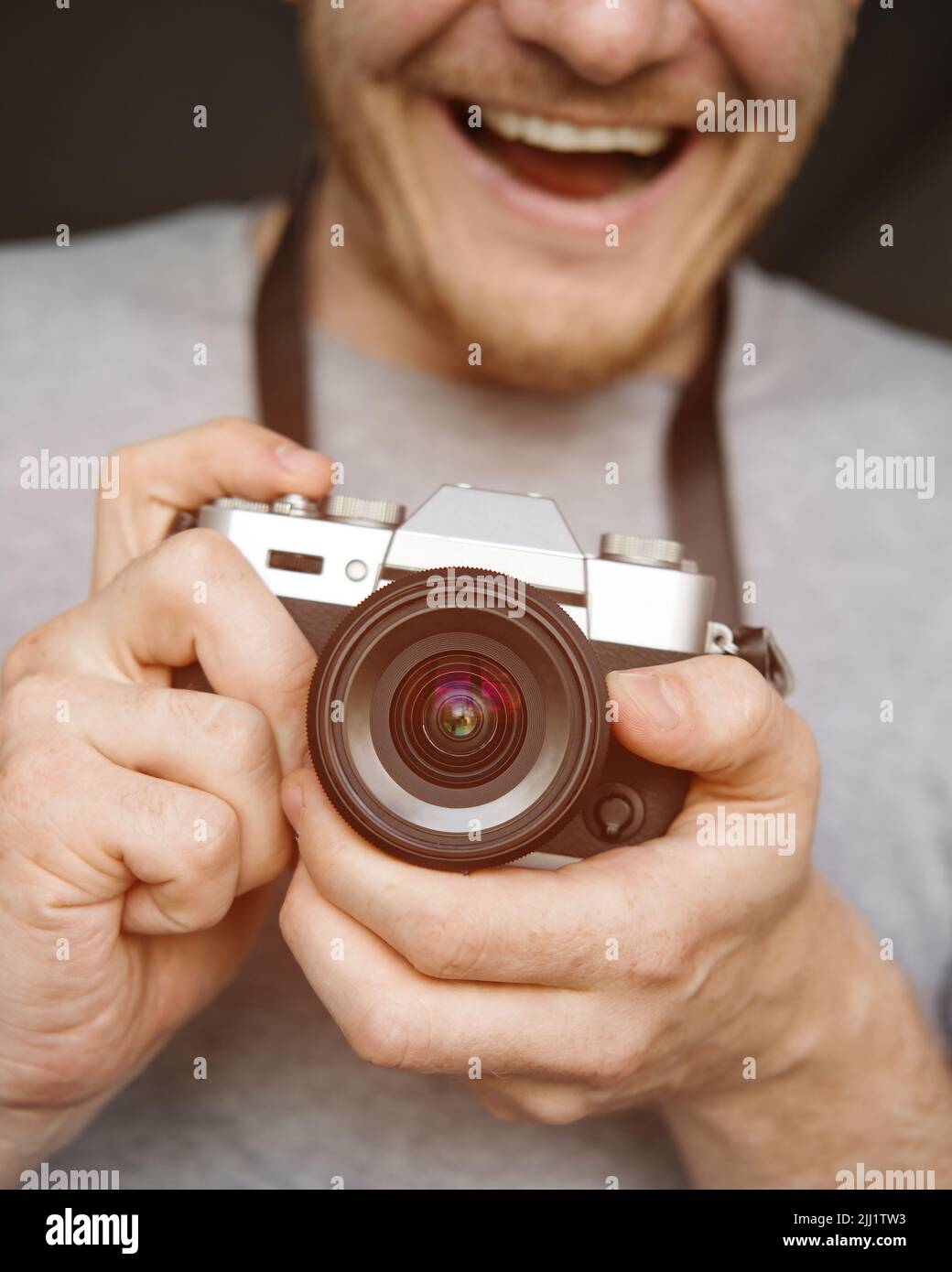 Un homme souriant tient un appareil photo rétro dans ses mains et fait une photo. Gros plan. Mise au point sélective. Banque D'Images