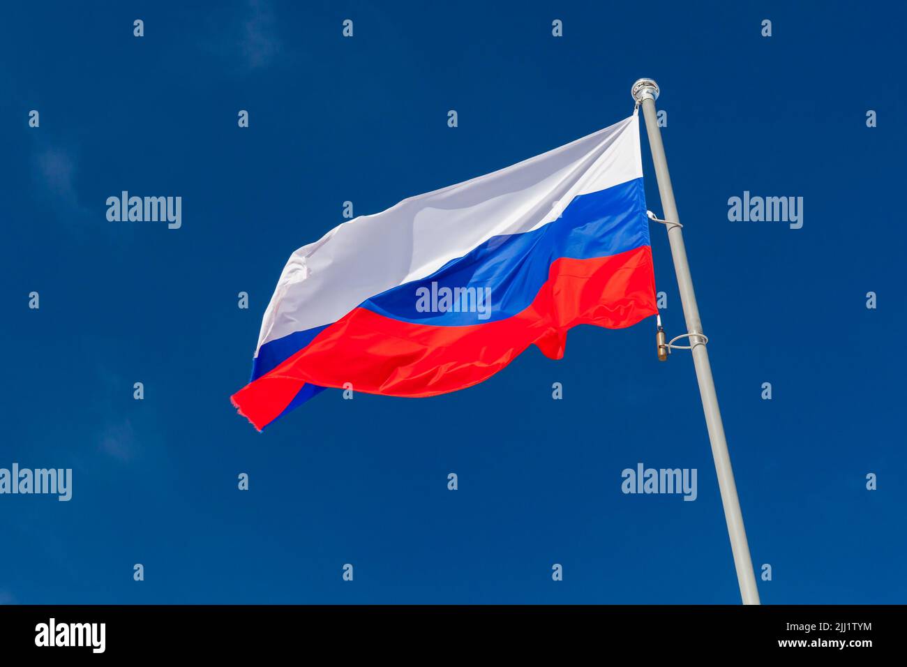 Le drapeau national de la Russie agite sur un mât blanc sous le ciel bleu par un jour ensoleillé Banque D'Images