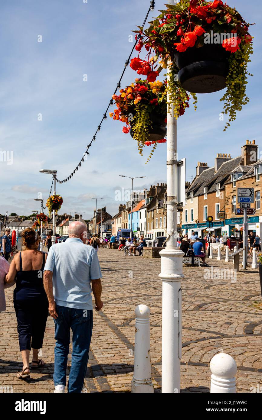 Promenade Anstruther près du port, avec des gens se promenant au soleil, avec des paniers suspendus et de la lumière Banque D'Images