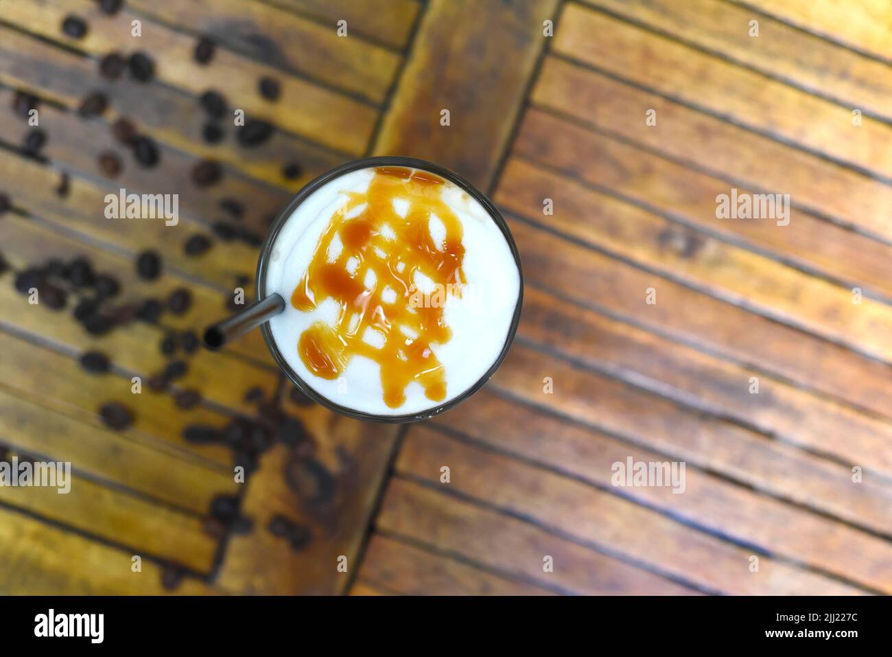 Latte au caramel glacé avec grains de café isolés sur une table en bois Banque D'Images