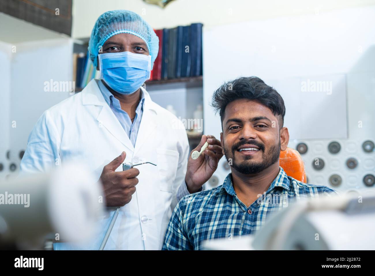Prise de vue portrait d'un patient souriant heureux avec un dentiste ou un dentiste avec un masque facial médical à l'hospice regardant la caméra - concept de soins buccaux Banque D'Images