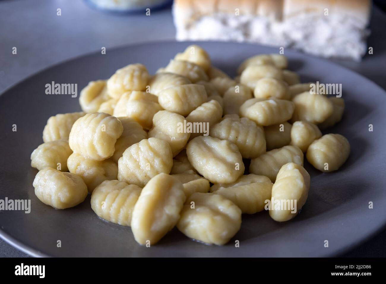 Assiette grise contenant une généreuse portion de gnocchi de pomme de terre fraîchement cuit. Banque D'Images