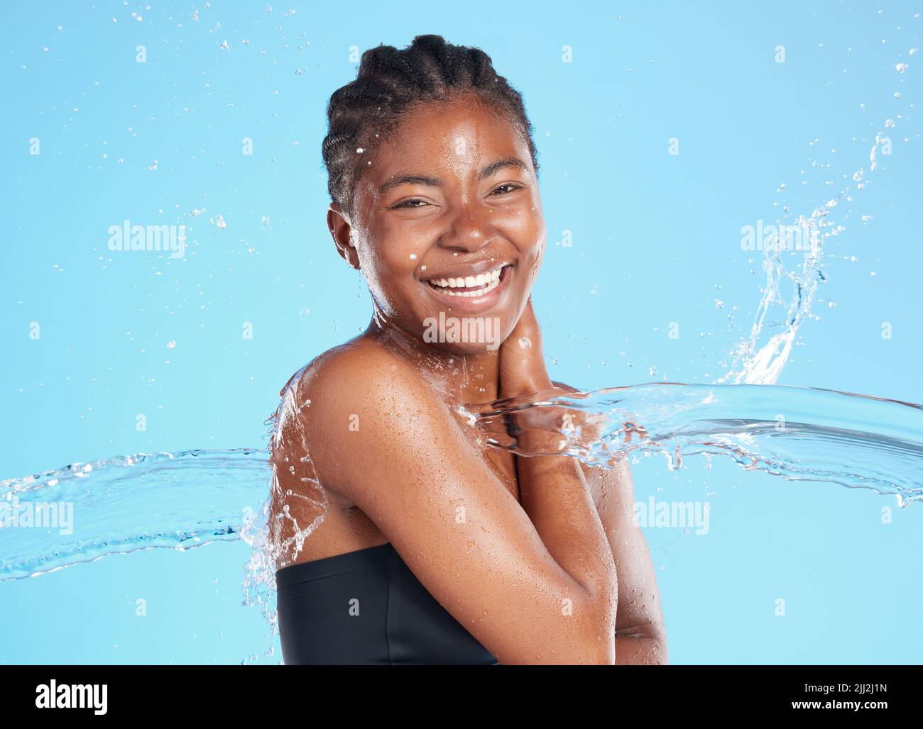 Vivre pour le moment. Une belle jeune femme éclaboussé avec de l'eau sur fond bleu. Banque D'Images