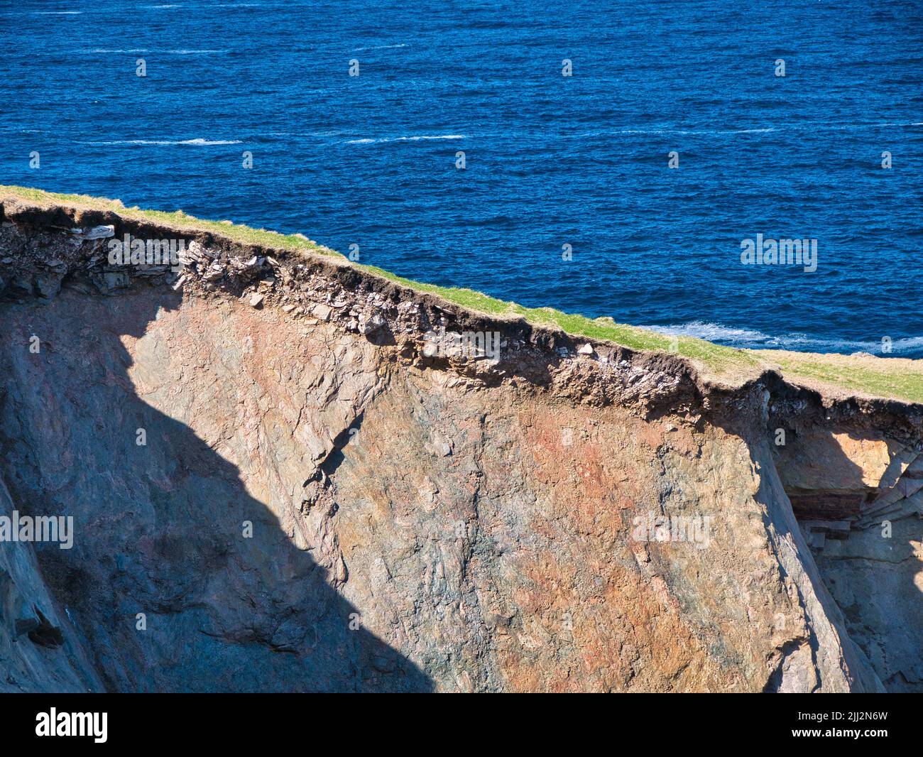 Sol érodé, sous-sol et soubassement rocheux sur des falaises abruptes près d'Uyea dans Northmavine, Shetland, Royaume-Uni. Pris par une journée ensoleillée avec la mer en arrière-plan. Banque D'Images