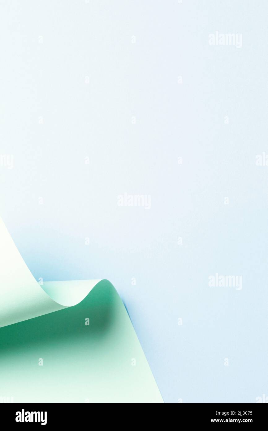 Vague abstraite de papier vert pastel sur fond bleu clair. Papier courbe géométrique créatif avec lumière et ombres. Arrière-plan de la géométrie abstraite Banque D'Images