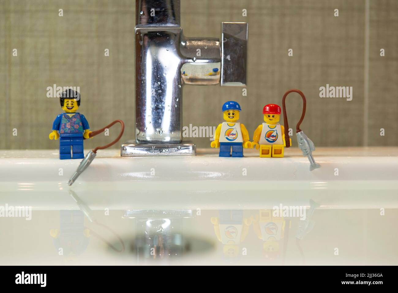 Bauru, Brésil. 7, juin, 2022: Gros plan de la mini figure de la pêche du Père et du fils heureux sur le bord d'un évier de salle de bains blanche. Père et fils avec pêche Banque D'Images