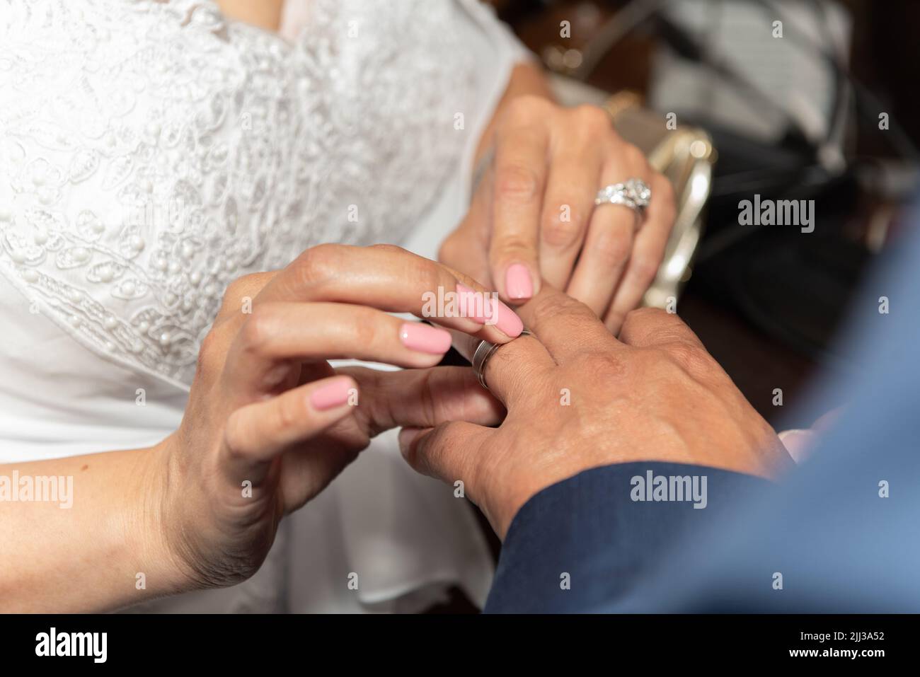 Mariée plaçant l'anneau sur le doigt du marié pendant la cérémonie de mariage du mariage. Banque D'Images
