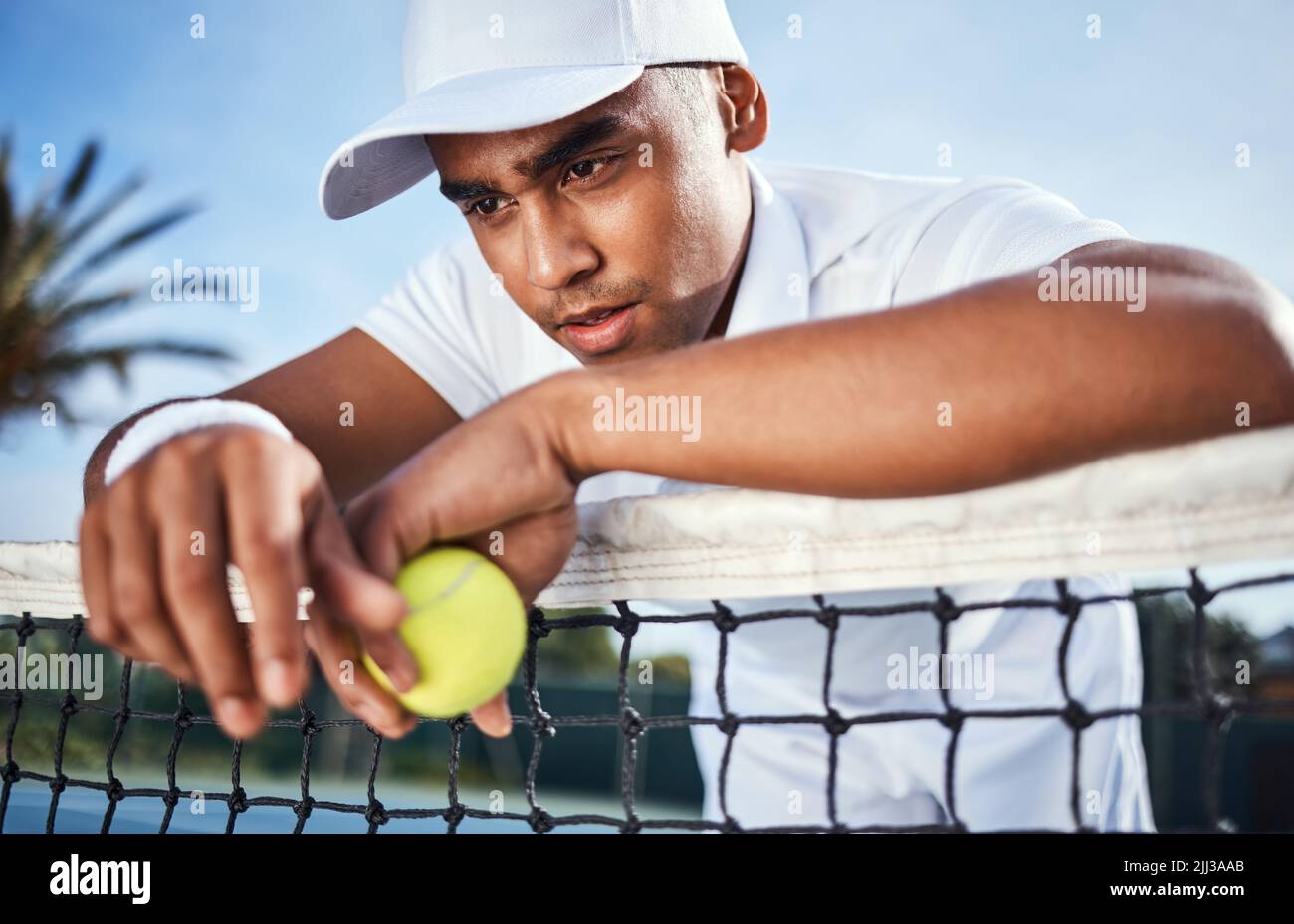 Ça ne me va pas. Un beau jeune homme s'est penché sur un filet de tennis et a l'air déçu après la pratique. Banque D'Images