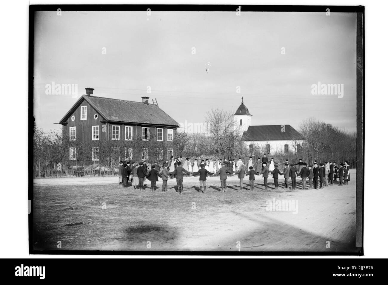 L'école de Lännäs et l'église de Lännäs. Bâtiment scolaire de deux étages, les écoliers à Ring dans la cour de l'école. Église en arrière-plan. Banque D'Images
