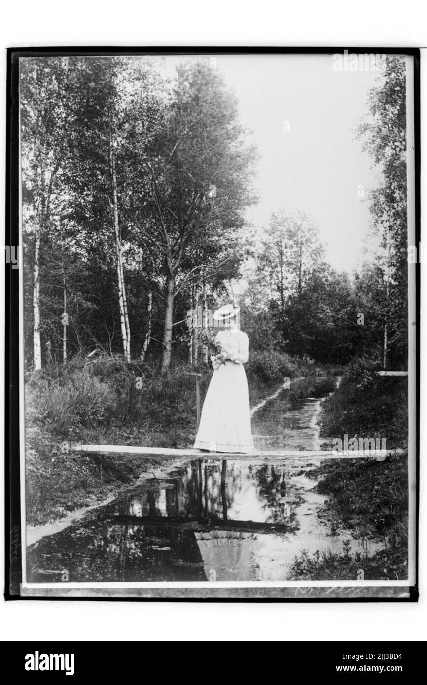 Une femme sur un sentier au-dessus d'un ruisseau dans la forêt. Mlle Hulda Johansson, fiancée du photographe Sam Lindskog. Banque D'Images