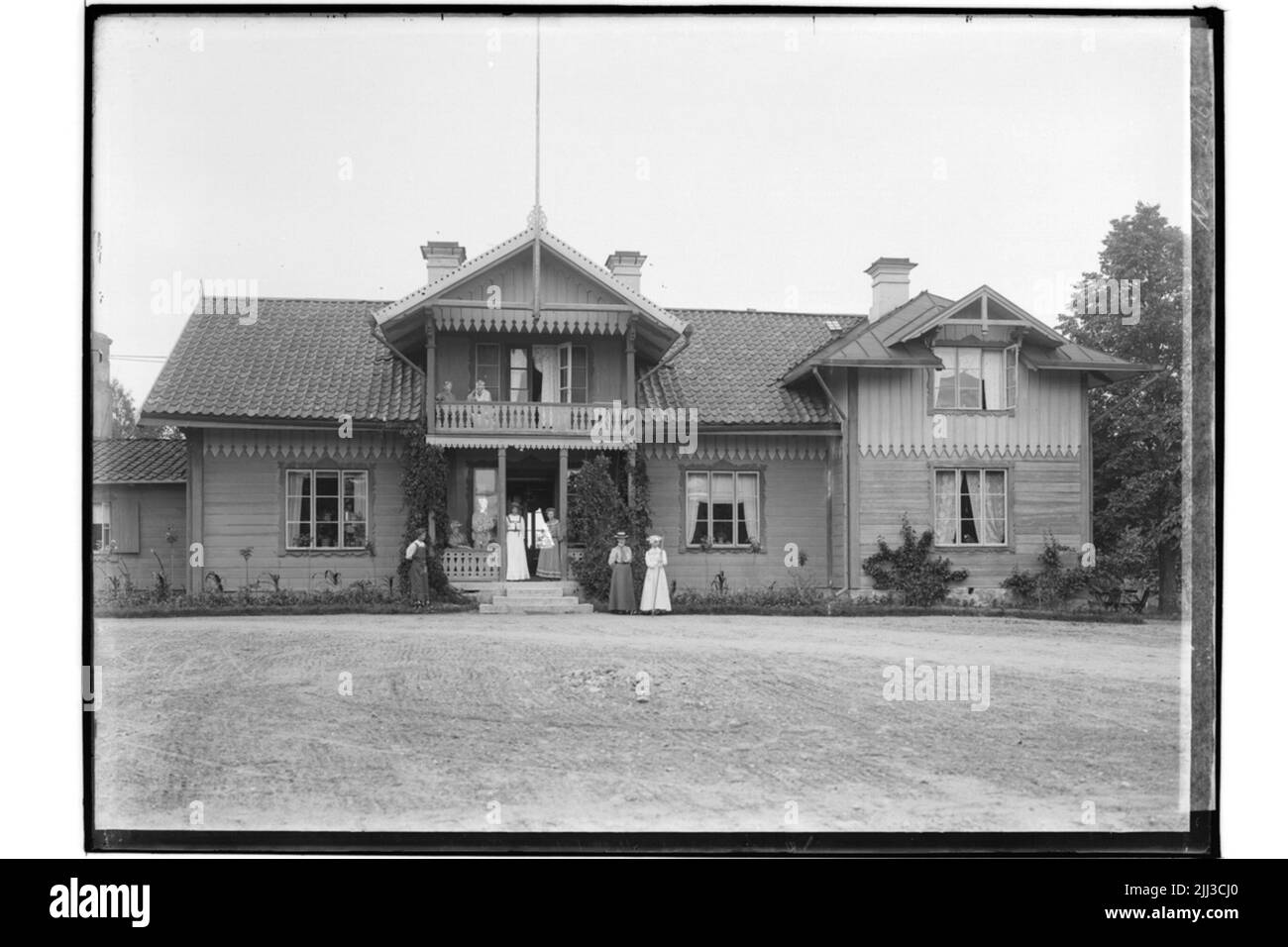 Bâtiments résidentiels d'un étage et demi, avec balcon et premier pont. 8 personnes en face de la maison. R. M. Noir Banque D'Images