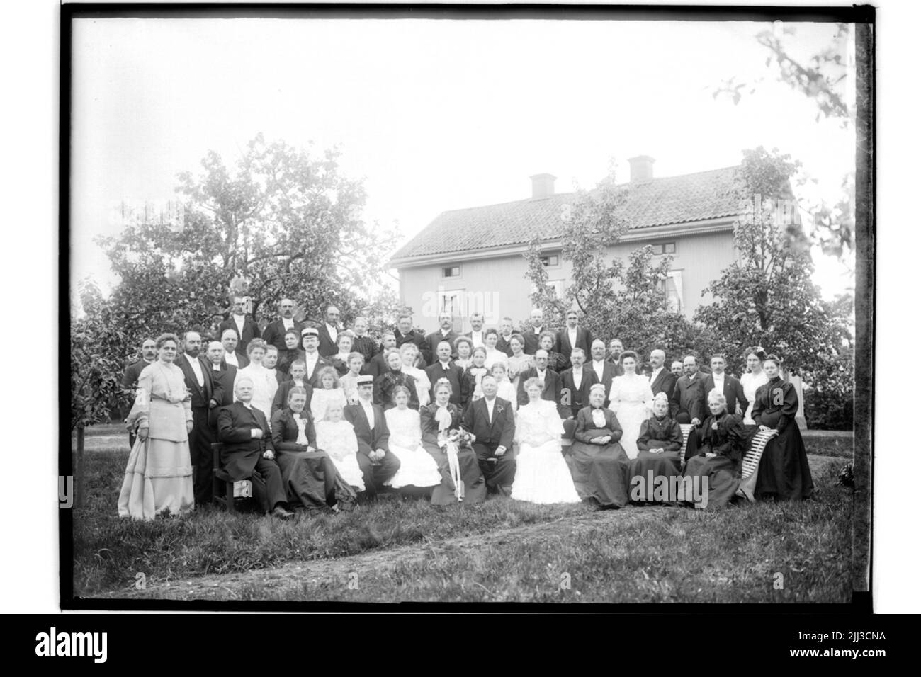 Bâtiment résidentiel et invités de mariage. La mariée en robe noire et voile blanc, couronne. Le marié dans frack.j.e. Morén Banque D'Images