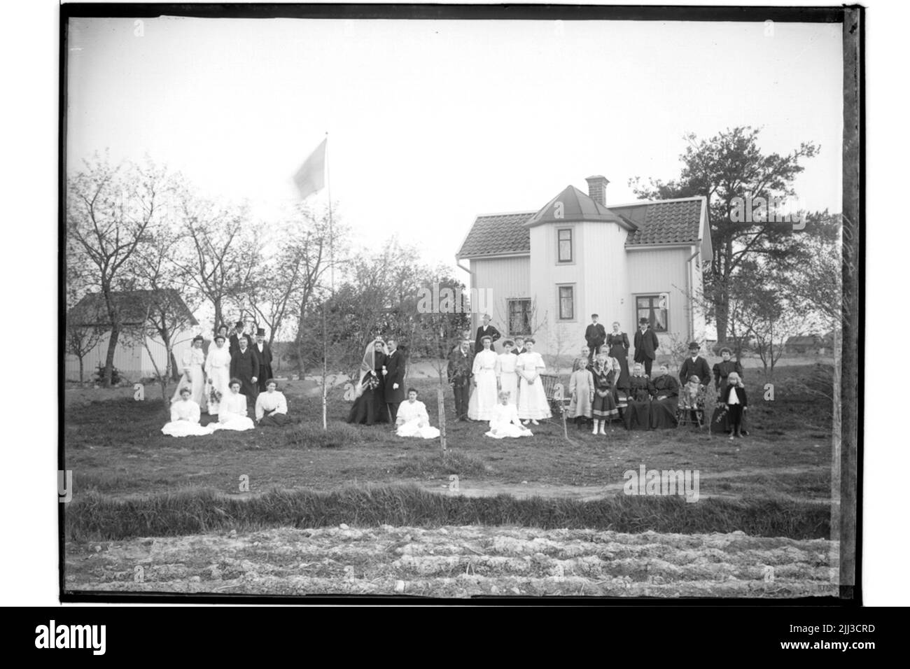 Bâtiment résidentiel de deux étages et invités de mariage. La mariée en robe noire, voile blanc, couronne. Le marié en manteau. A.G. Johansson Banque D'Images