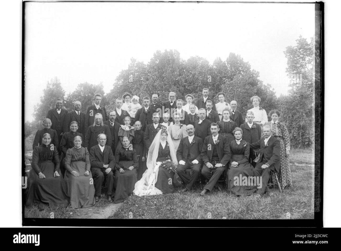 Couple de mariage et invités de mariage. La mariée en robe noire, voile blanc, couronne. Le marié dans le manteau. Johan Jonsson Banque D'Images