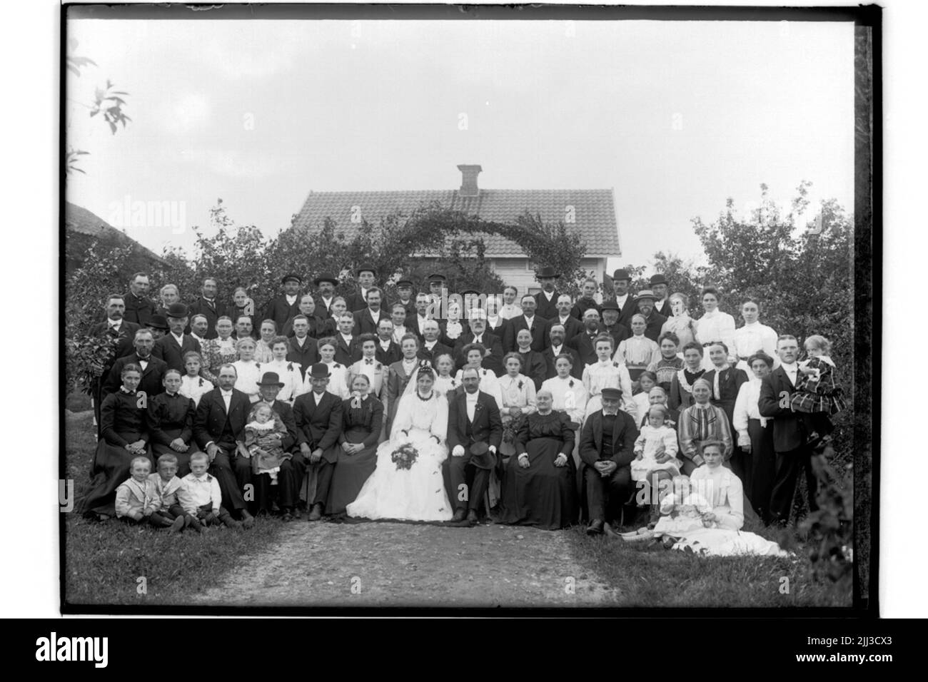 Couple de mariage et invités de mariage. La mariée complètement en blanc avec voile et couronne. Le marié en manteau et chapeau haut.p.j. Eriksson Banque D'Images