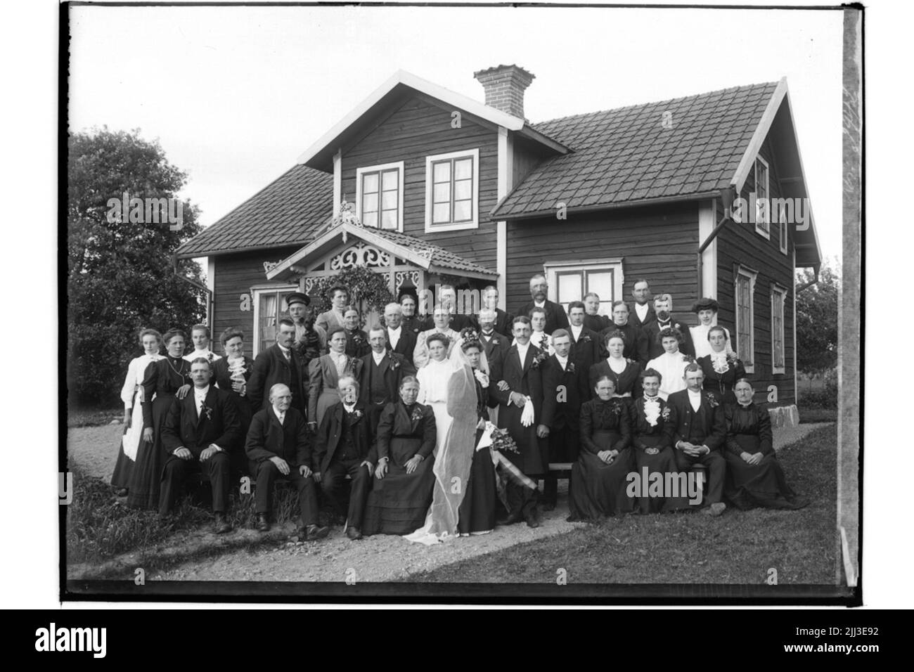 Bâtiments résidentiels à un et demi-niveau. Mariage, couples mariés et invités de mariage. La mariée en robe noire, voile, couronne. Le marié en manteau.per Erik Andersson Banque D'Images