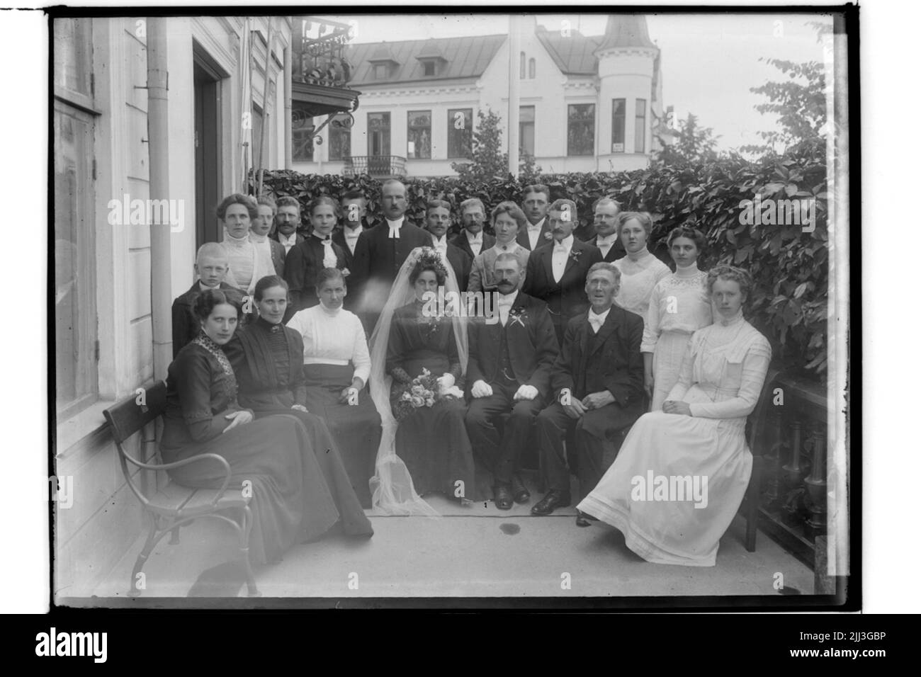 Mariage, couples mariés et invités de mariage. La mariée en robe noire, voile blanc, couronne. Le marié dans frack.aug. Jansson Banque D'Images