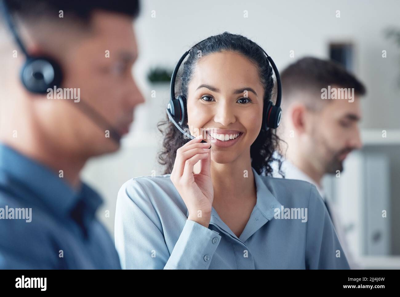 Appelez-moi, j'aime parler. Portrait d'un jeune agent de centre d'appels travaillant dans un bureau aux côtés de ses collègues. Banque D'Images