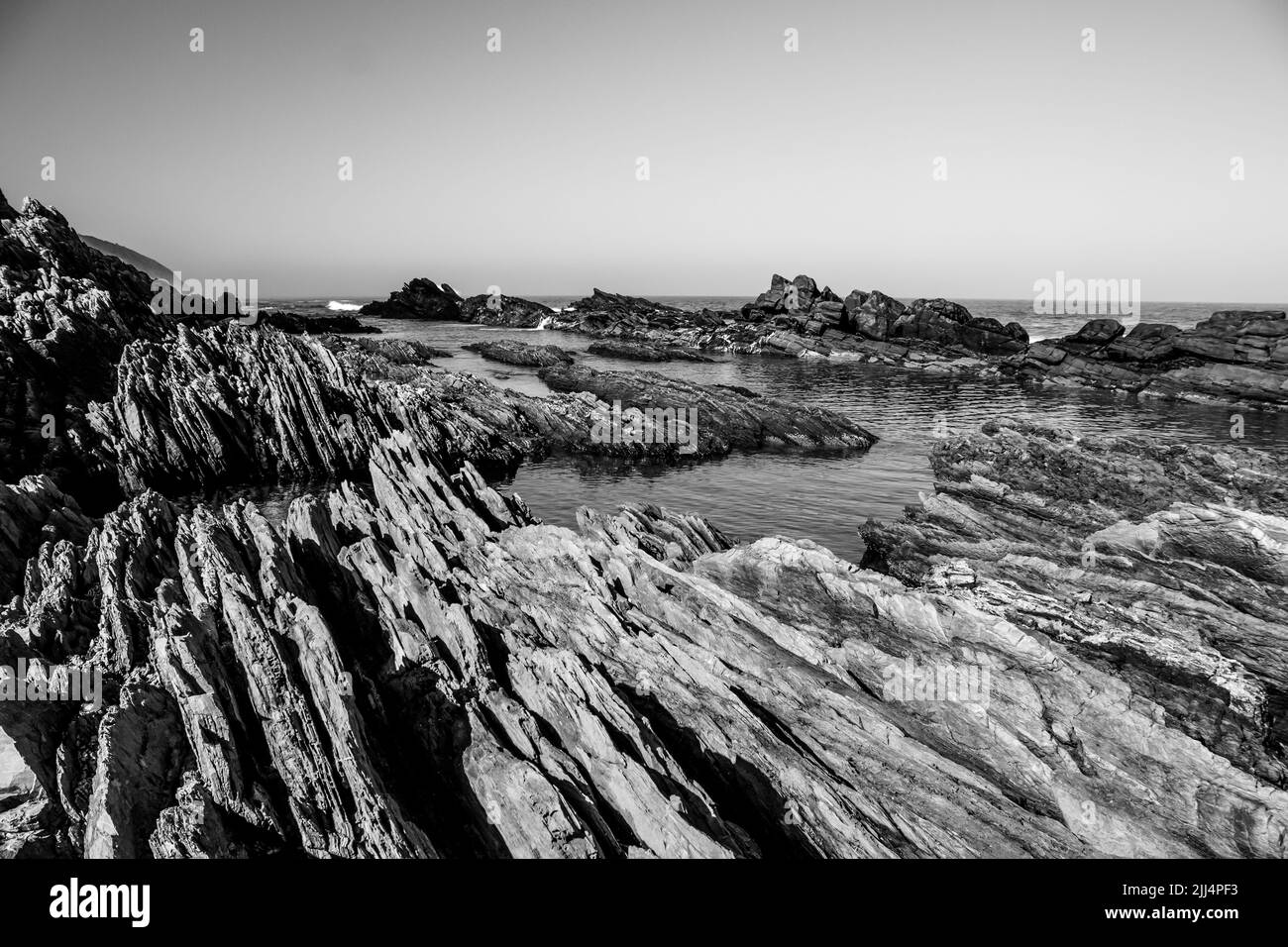 Vue en noir et blanc de la côte rocheuse déchiquetée de la section Tsitsikamma du parc national Garden route, Afrique du Sud Banque D'Images