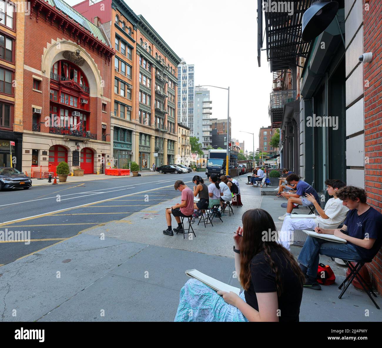 Étudiants en art avec des sketchpads dessinant le foyer sur Great Jones St à Manhattan, New York, 20 juillet 2022. Banque D'Images