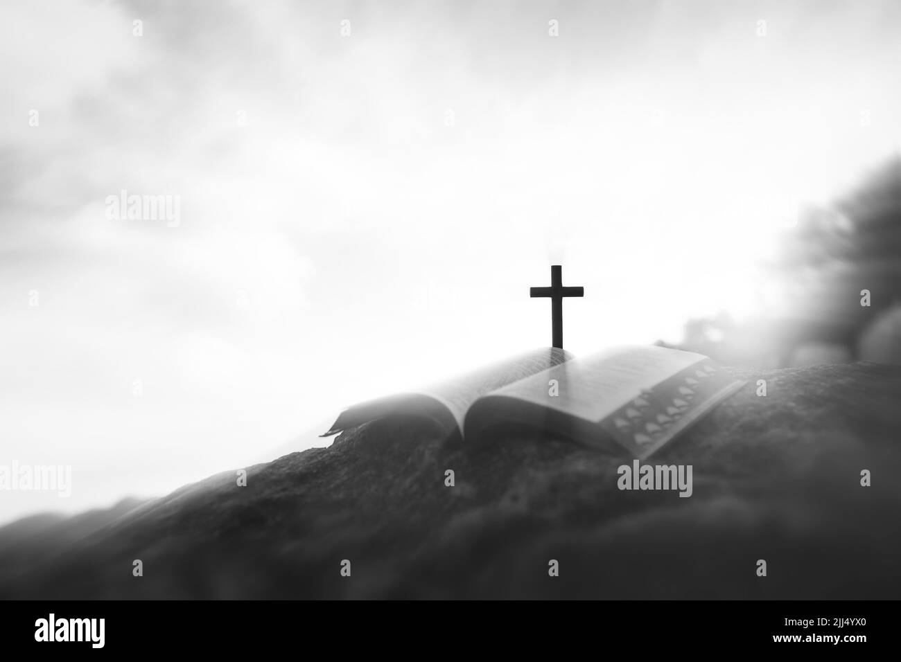 Entre le ciel lumineux et les nuages, la croix de souffrance de Jésus-Christ symbolisant le sacrifice et la résurrection, et la sainte bible sur la colline Banque D'Images