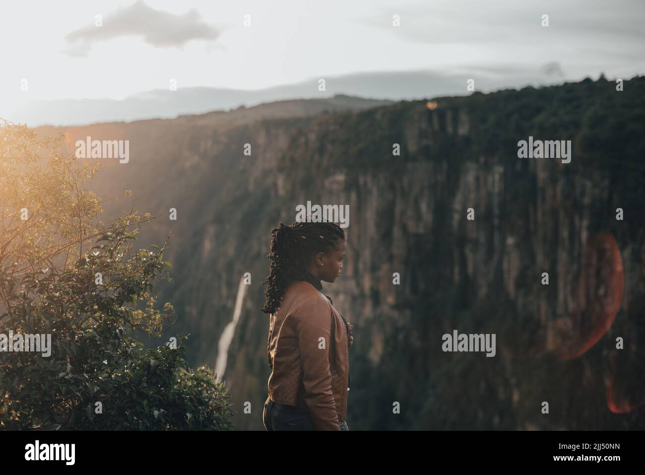 Jeune femme debout sur la falaise au coucher du soleil Banque D'Images