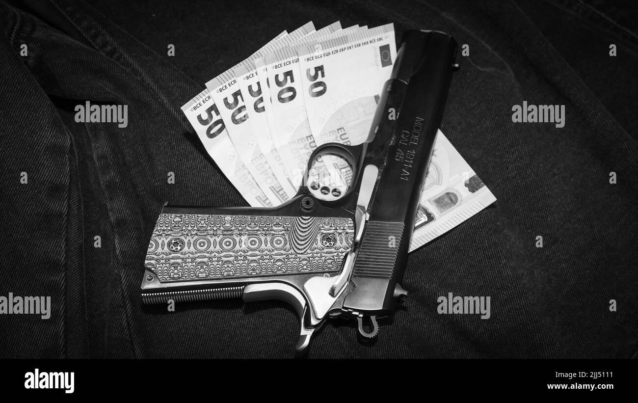 Pistolet à main avec poignée décorative sur des billets en euros, photo monochrome Banque D'Images