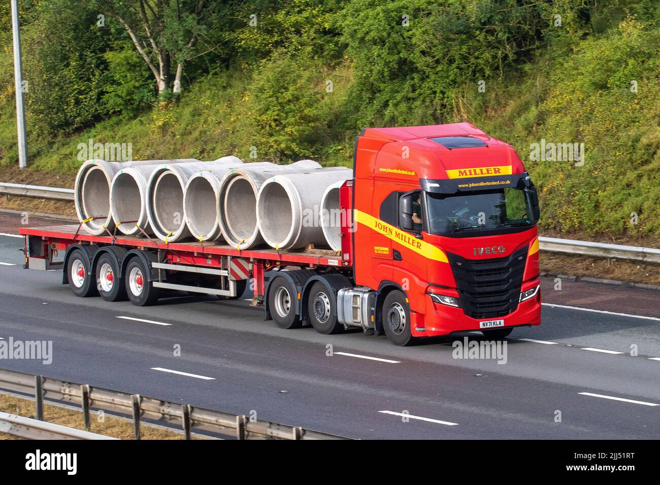 John Miller Limited 2022 IVECO STRALIS 12882cc camion à plateau transportant des sections de drainage en béton, voyageant sur l'autoroute M6 UK Banque D'Images