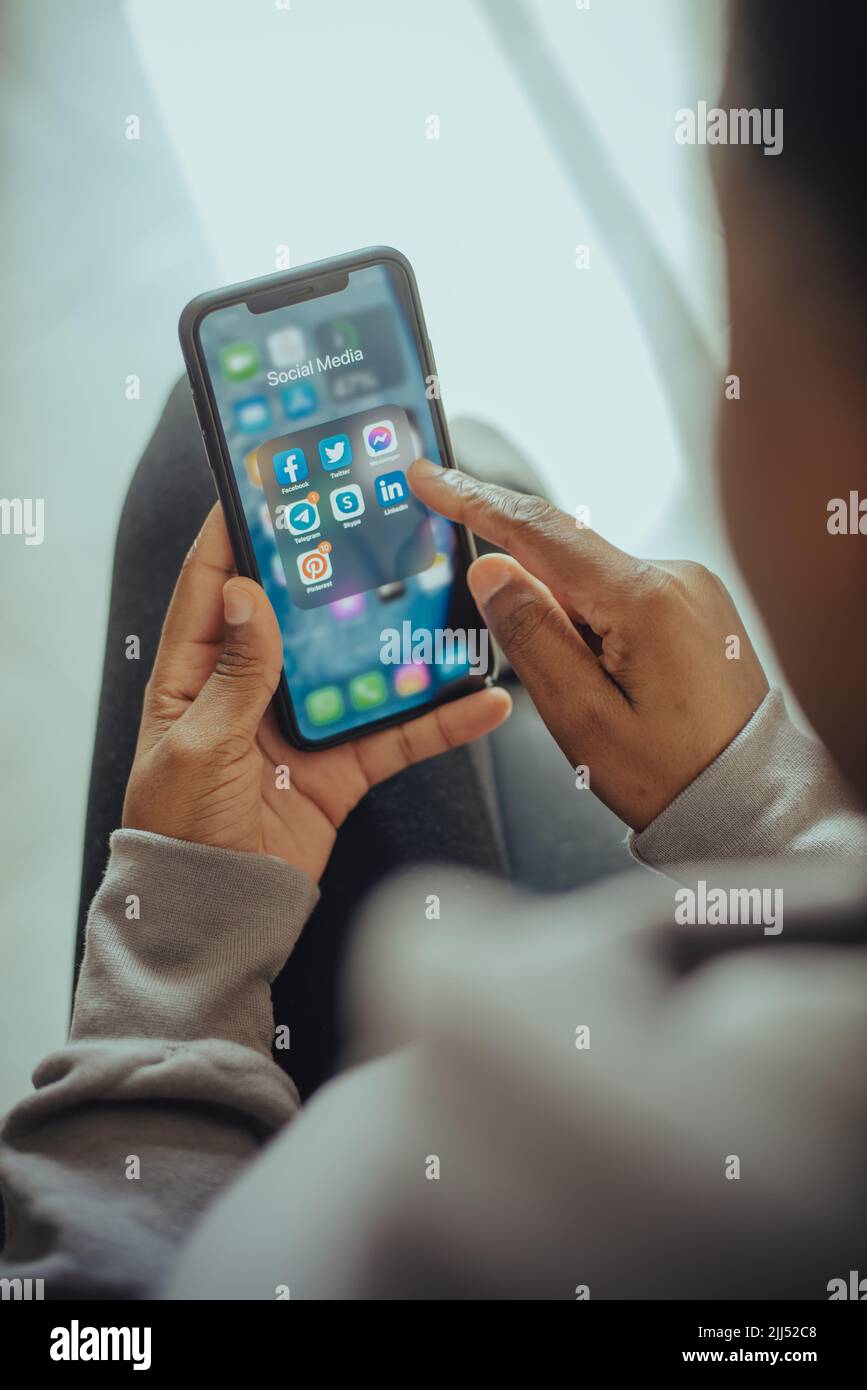 Mains d'une personne tenant un téléphone portable avec des icônes de réseaux sociaux affichées à l'écran Banque D'Images