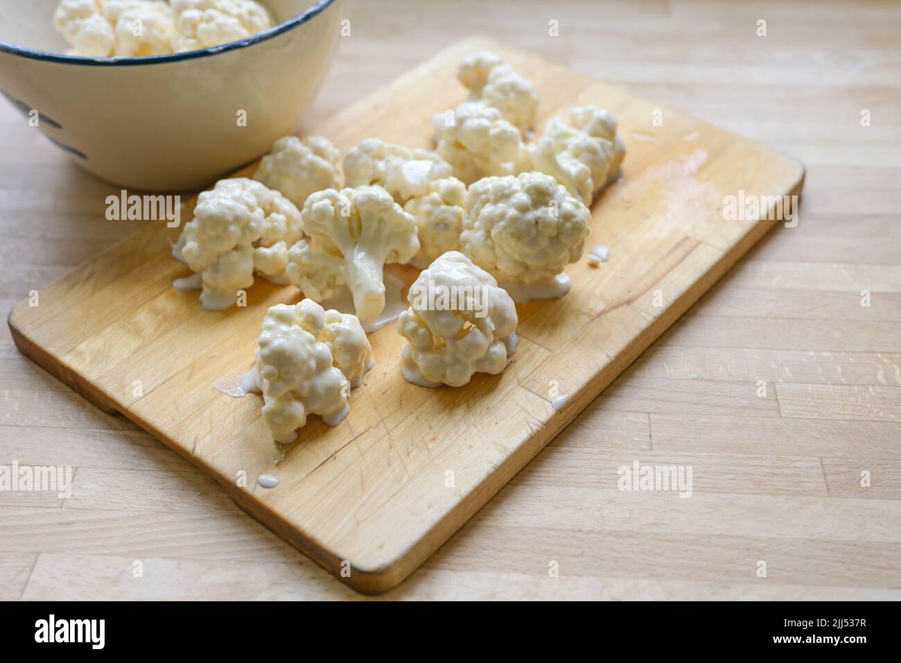 Morceaux de chou-fleur enrobés de pâte épicée sur une planche à découper en bois comme préparation pour la friture, la cuisine végétarienne avec des légumes, l'espace de copie, selec Banque D'Images